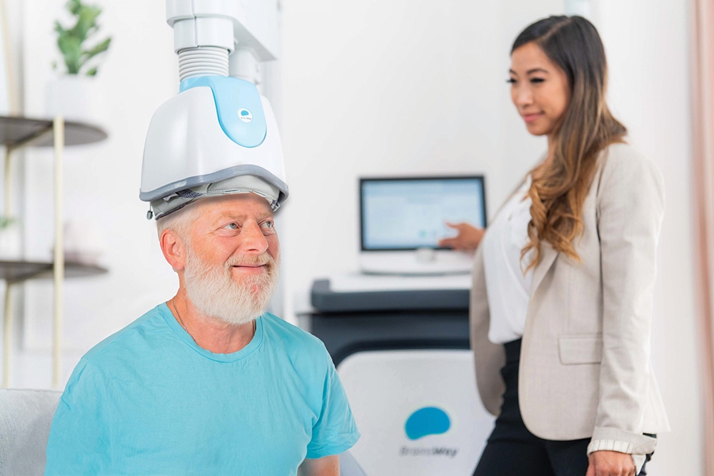 A gentlemen receiving TMS Therapy with a Brainsway helmet device.