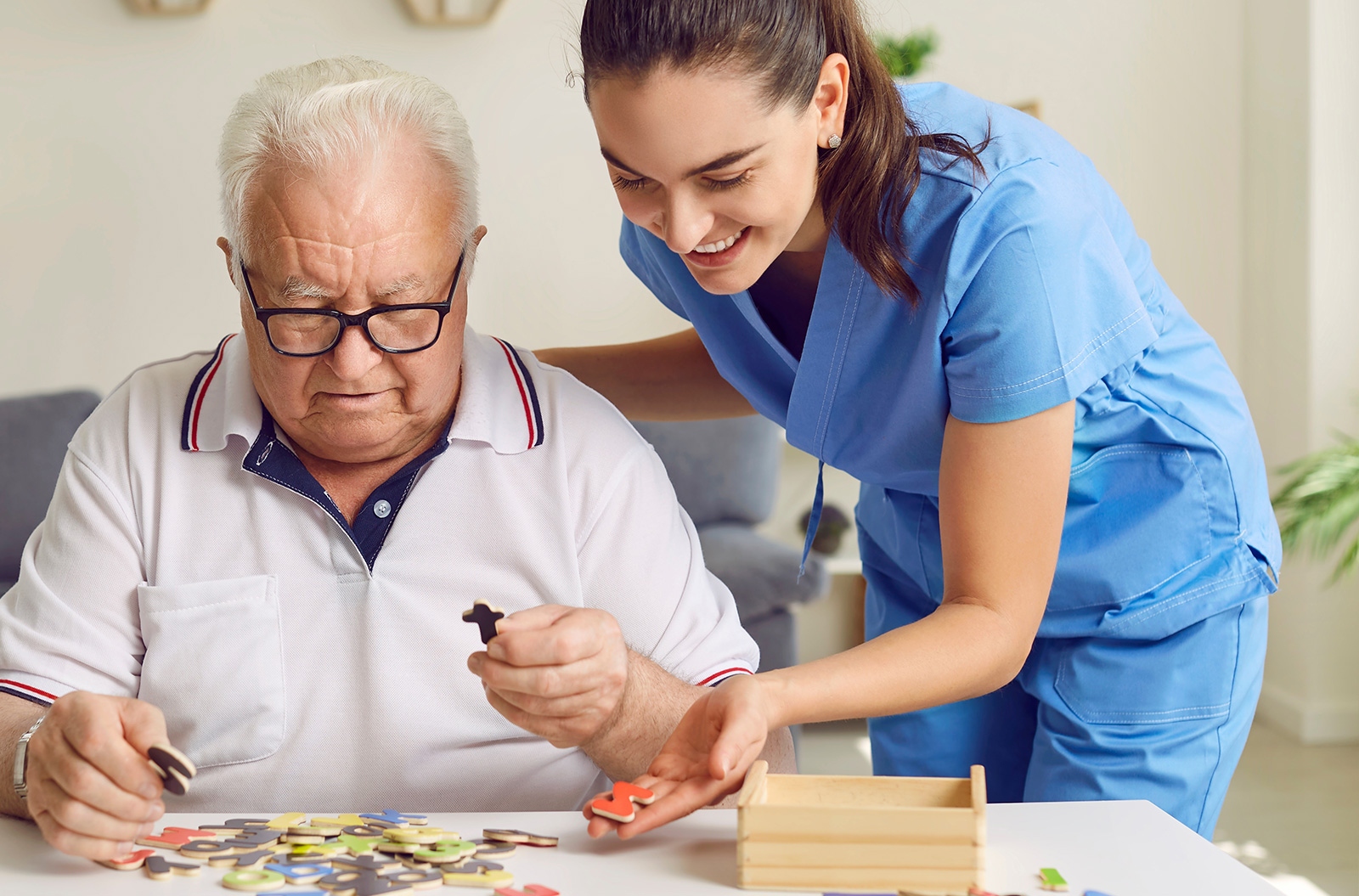 Senior and caretaker or doctor helping identify puzzle pieces during a neurology screening.