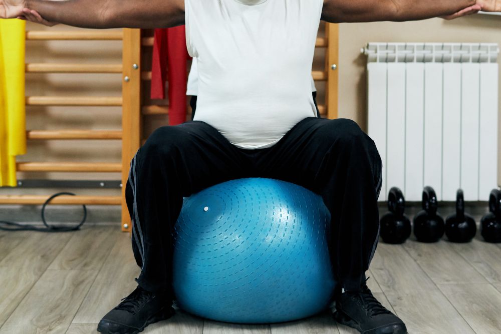 A man sitting on a large blue balance ball during Plymouth Meeting vestibular rehabilitation.