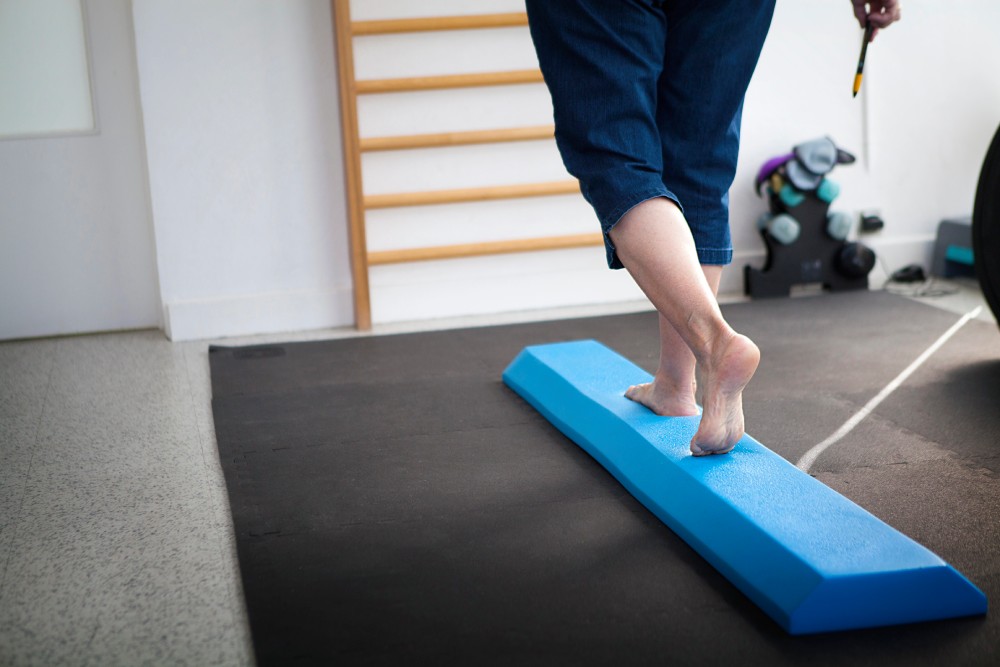 A patient balancing on a piece of blue foam as part of Cedar Hill, Blue Bell dizziness therapy.