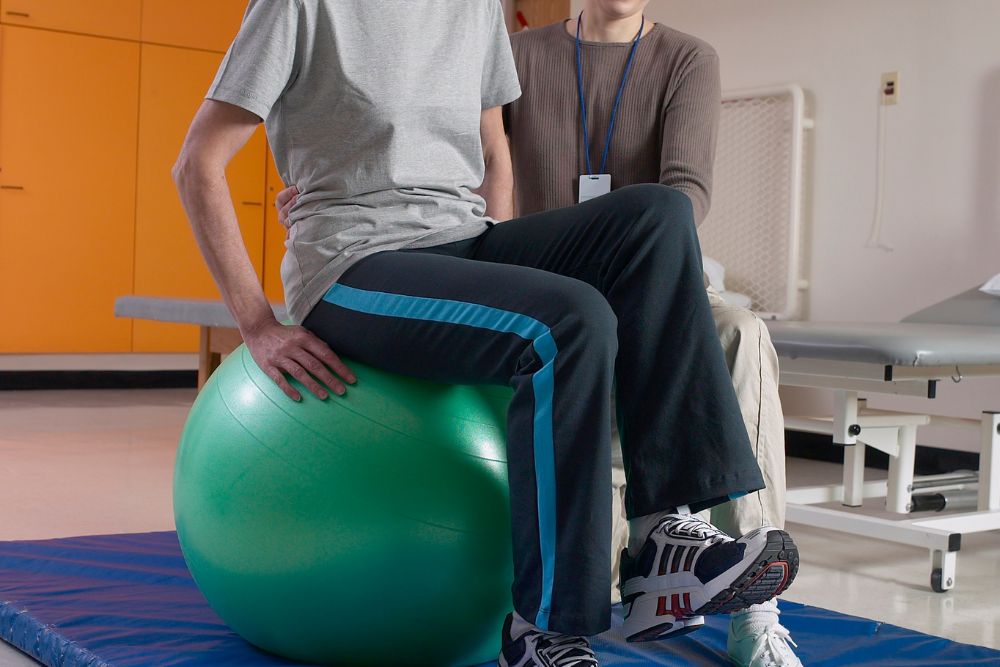 A male patient sitting on a green balance ball during vestibular therapy near Gwynedd Valley, Pennsylvania.