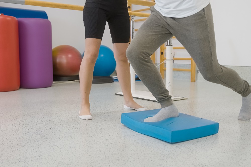 A physical therapist overseeing a patient doing exercises as part of West Norriton FMD treatment.