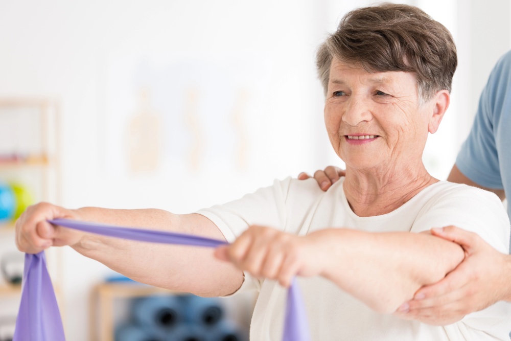 A female patient holding a training band in both hands as part of stroke rehabilitation physical therapy near Fort Washington, Pennsylvania.